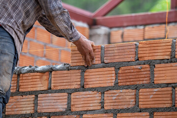 Red bricks and mason are building bricks to build the walls of the building. Working requires professional skills. A balanced mix of mortar and leveled bricks.