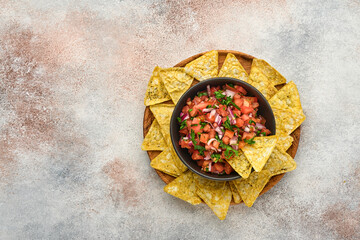 Obraz na płótnie Canvas Traditional Mexican tomato sauce salsa with nachos and ingredients tomatoes, chile, garlic, onion on light slate stone background. Concept of Latin American and Mexican food. Mock up.
