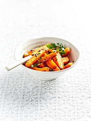 Oven roasted carrots with fresh parsley served in a bowl on vintage table cloth