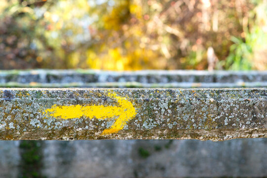 yellow arrow sign  painted in stone bridge on way to Santiago of Compostela  near Hospital of Orbigo village , Leon , Spain