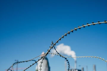 barb wire in front of blurry industrie