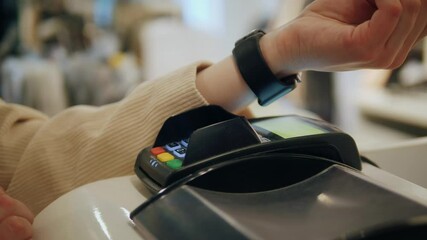 Customer paying with NFC technology by smart watch contactless on terminal in the shop. - Powered by Adobe