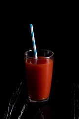 Red cocktail with tomato juice in a clear glass, dark tone picture.