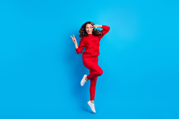 Fototapeta na wymiar Full length body size photo of woman wearing casual outfit jumping high showing v-sign gesture isolated on vibrant blue color background