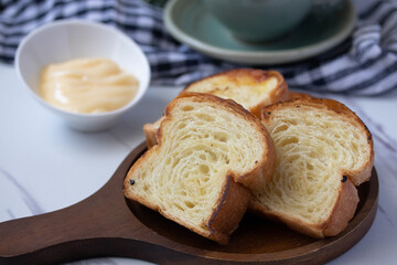 Toast in wooden plate with cheese on gray background
