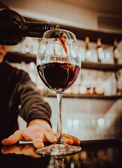 bartender pouring red wine into a glass in cafe or bar