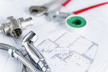 Plumbing project in house.Drawing,diagrams,plan of water supply of apartment,building.Man repairer making repairs at home.Devices,accessories, hose,tap,adjustable wrench,pressure reducer,tape measure