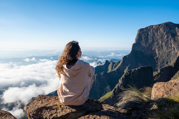 Woman sit on the top of the mountain and enjoy the view of the valley. Drakensberg mountains. Beyond the clouds - 430617987