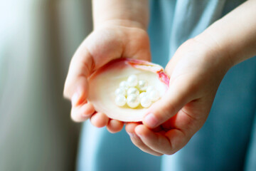 Children's hands hold oyster shell with pearls	