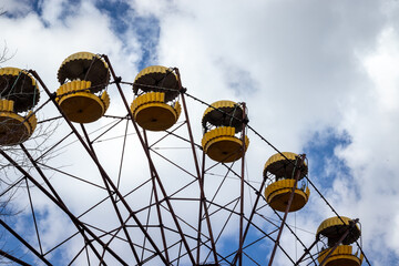 Old abandoned rusty metal radioactive yellow ferris wheel against dramatic sky in amusement park in ghost town Pripyat, Chernobyl Exclusion Zone