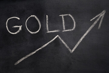 Fototapeta na wymiar the price of the gold is very high. simbol of an up arrow and the word gold written on a blackboard.
