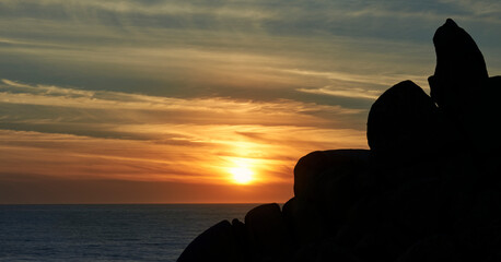 silhouette of a mountain of rocks against the light and beautiful sunset over the sea