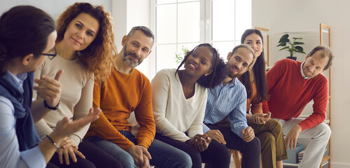 Group of interracial people sit in a row and listen with interest to a man telling his story....