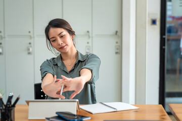 Asian businesswoman sitting and stretching at the office