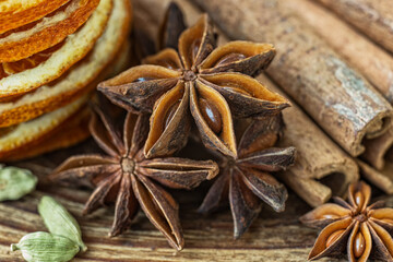 Dry orange slices, anise stars, cinnamon, cardamom and roasted coffee beans on a wooden table. 