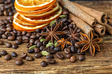 Dry orange slices, anise stars, cinnamon and roasted coffee beans on a wooden table. 