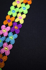 Very beautiful and creative placement of colorful small floral laces at the side of matte black textured background