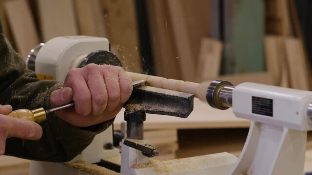 Close up. Carpenter at workshop polishes wooden board with a electric orbital sander. Woodwork and furniture making concept.