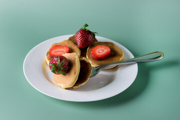 Freshly Baked American Mini Pancakes on a Fork With Fresh Berry Tasty Breakfast Green Background Horizontal