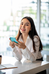 Obraz premium Young woman using smartphone at home. Student girl texting on mobile phone in her room. Communication, home work or study, connection, mobile apps, technology, lifestyle concept