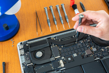  A technician's hands repairing disassembled laptop