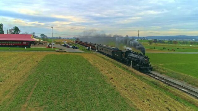 Strasburg, Pennsylvania, November 2020 - An Aerial View of an Antique Restored Steam Train and Passenger Coaches Approaching With Smoke and Steam