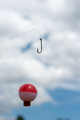 round plastic float and fish hook against a mostly cloudy sky