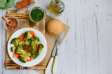 Diet food concept. Steamed vegetables, bran bread, spices and herbs on a wooden background. Top view, copy space