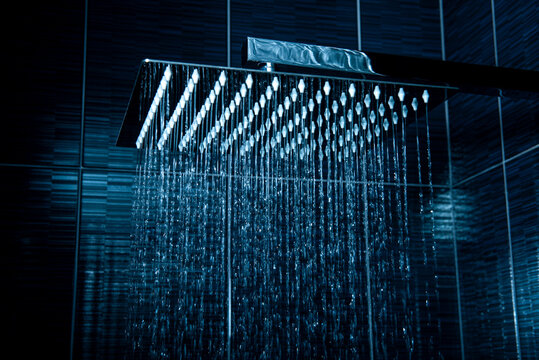 Quadratic chrome shower head with flowing water.