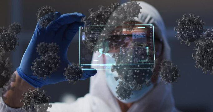 Animation of covid 19 cells over scientist in ppe suit holding screen with medical data processing