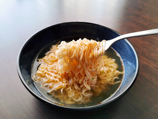 Instant noodles on fork on a blue bowl. 