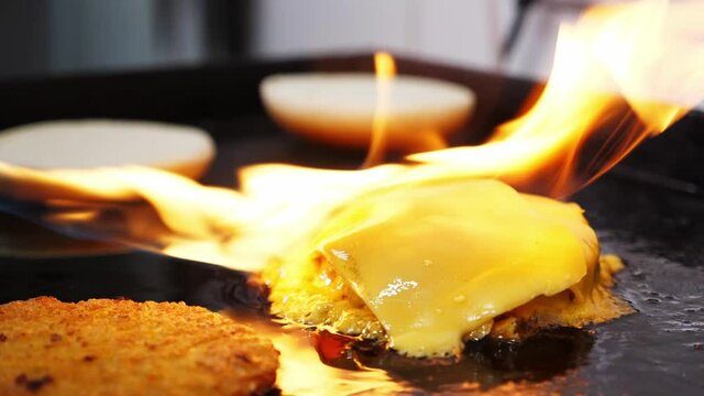  Chef is melting cheese on burger meat cutlet with fire from gas burner, close-up in slow motion. Cooking, barbecue and fast food concept. High quality HD footage