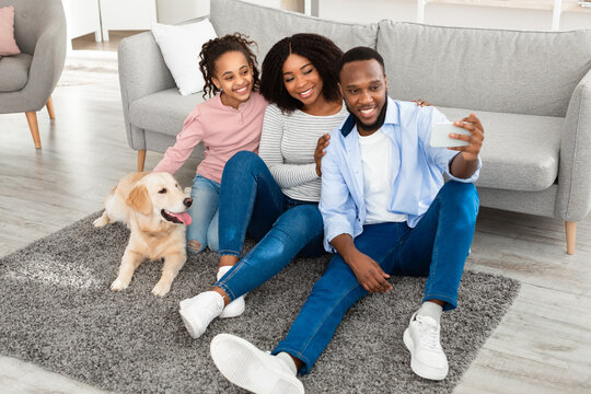Young black family taking selfie with dog at home
