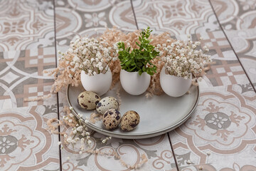 Easter composition. White eggs with funny faces painted on the table. A small bouquet in an egg. The minimal concept of Easter.