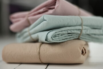 photo with 3 colors (pink, mint, beige) of natural and ecological washed cotton fabrics stacked on top of each other on white background