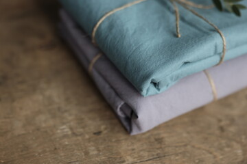 photo of 2 natural and ecological washed cotton fabrics in grey and turquoise colours rewound with sack thread and green plant on it