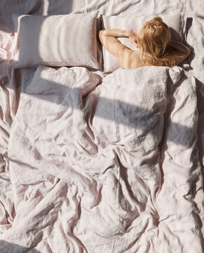 Photo Of A Beautiful Blond Woman Lying In A Linen Pastel Bedding Back To Us, She Has A Lot Of Cute Freckles On Her Back