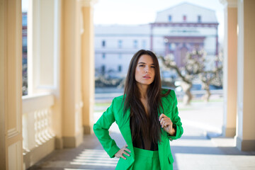 graceful caucasian female in a green suit and black blouse is staying in the shadow of arch of the ancient theater