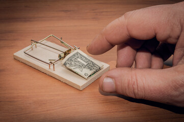Man try to steal a one dollar bill banknote from a mouse trap