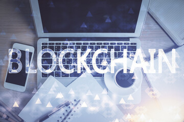 Blockchain theme hologram drawings over computer on the desktop background. Top view. Double...