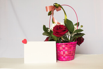 Flower basket with fragrant flowers, red and pink roses on a light background. Space for text or image. Valentine's Day, Anniversary, Wedding concept, Holidays