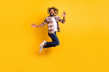 Fototapeta na wymiar Full length body size photo of man jumping high wearing casual clothes laughing isolated on vivid yellow color background