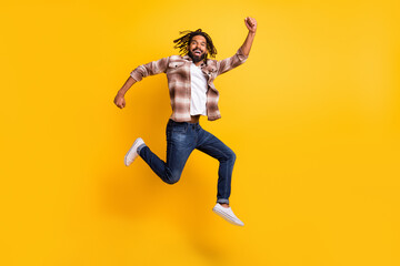 Full length body size photo of cheerful jumping man gesturing like winner isolated on bright yellow color background