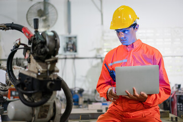 Male engineer checking robotic arm machine for system welding with remote control at a factory Industrial