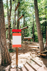Blank sign in red edging in the forest near the rope park