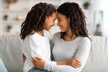 Cute black mother and daughter cuddling at home