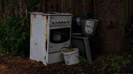 A damaged gas stove and a TV set left under the tree. 
Scrap 