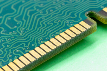 Close-up gold contacts of computer memory module on green background. RAM memory detail. Concept electronic design.  