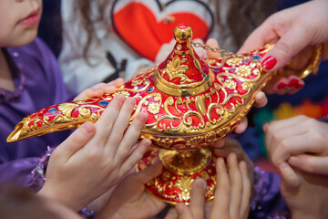Golden Red Old magic lamp . They touch the old magic lamp with their hands .