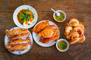 Top view Boiled Crabs and Shrimps in the white ceramic and glass dish on the vintage wooden table.